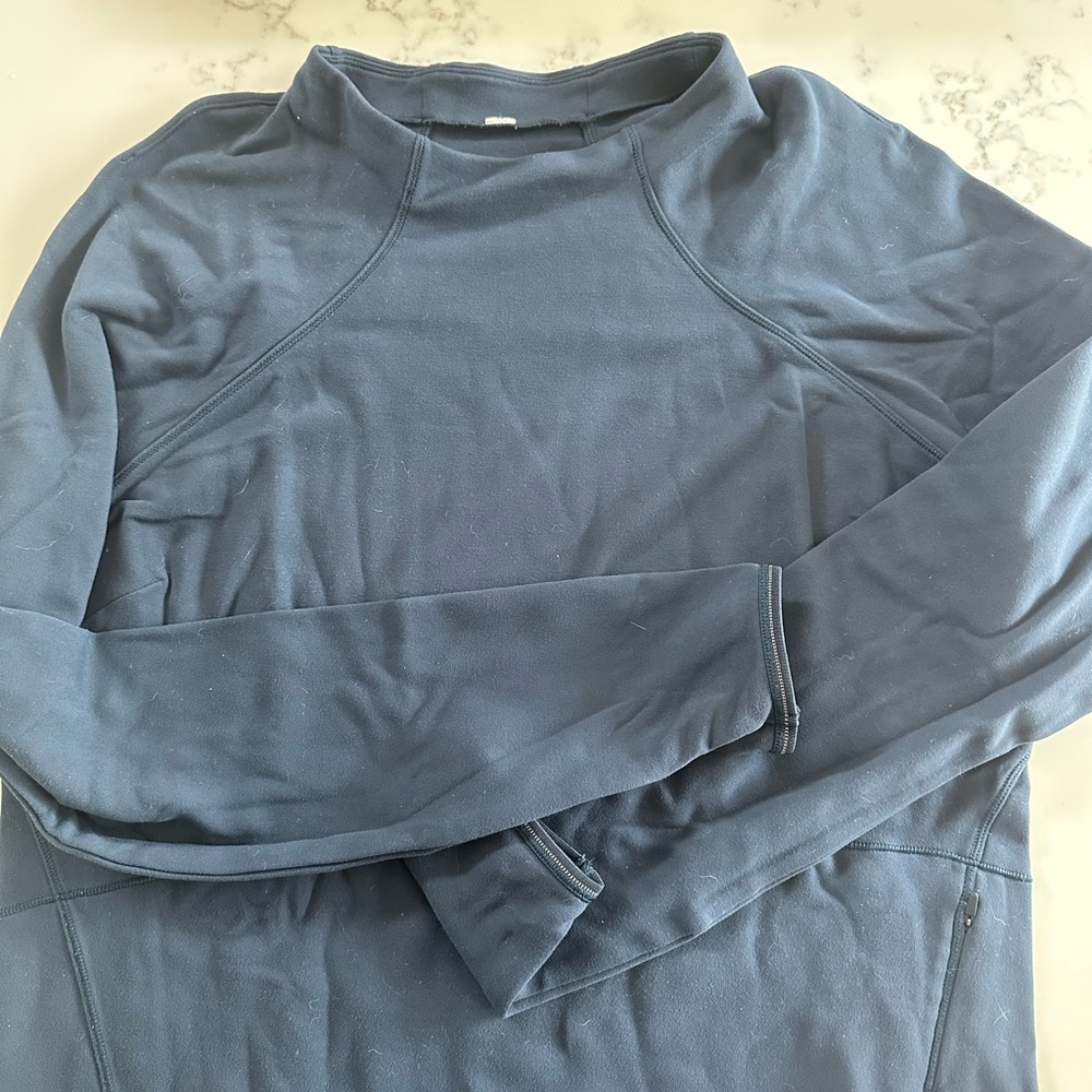 Lululemon navy long sleeve pullover with zipper pocket detail on side.